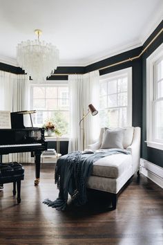 a living room filled with furniture and a grand piano in front of two large windows