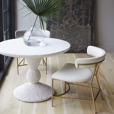 a white table with two chairs and a vase on it in front of a window