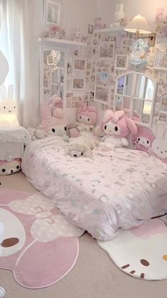 a bedroom decorated in pink and white with lots of stuffed animals on the bedding