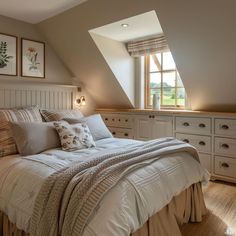 a large bed sitting under a window in a bedroom next to a dresser and drawers