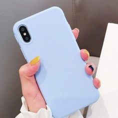 a woman holding up her phone case with yellow and blue nail art on the back