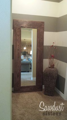 a large mirror sitting in the corner of a room next to a vase with flowers