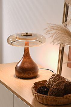 a table lamp sitting on top of a wooden counter next to a basket with fruit