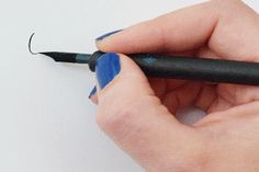 a woman's hand holding a black pen and writing on a piece of paper