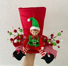 an elf doll sitting on top of a red chair with green and white striped stockings