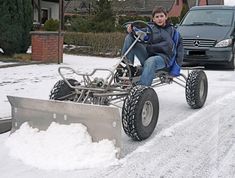 a man sitting on top of a snow plow in the middle of a road