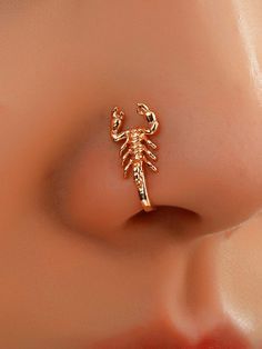 a close up view of the nose with a scorpion earring in gold plated brass