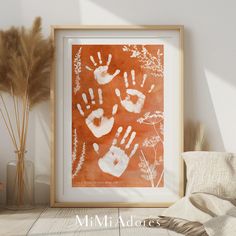 an orange and white painting with handprints on it next to some dried plants