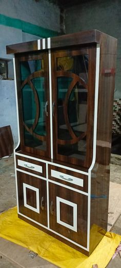 a wooden display cabinet with glass doors on the front and sides, sitting on top of a piece of cardboard