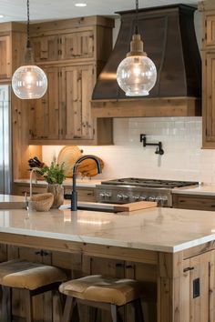 a large kitchen with wooden cabinets and marble counter tops, two pendant lights hanging over the island