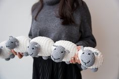 a woman is holding four knit sheeps in her hands