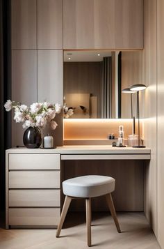 a white stool sitting under a mirror next to a desk with flowers on top of it