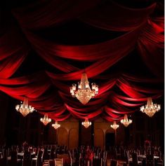 a room with red drapes and chandeliers