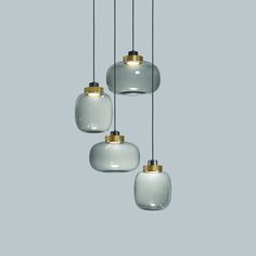 three white and gold glass pendants hanging from a ceiling fixture in a room with gray walls