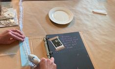 a person is writing on a piece of paper at a table with other items and utensils