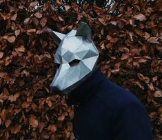 a man wearing a paper mask standing in front of leaves