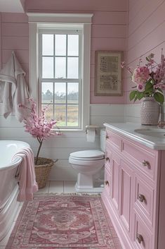 a bathroom with pink walls and flooring has a rug in front of the tub