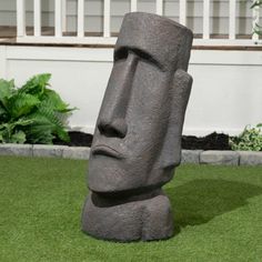 a large stone statue sitting on top of a lush green field