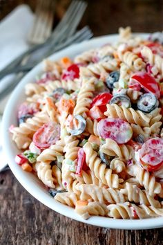 a bowl filled with pasta salad on top of a wooden table