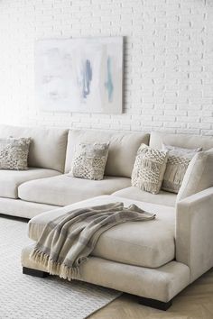 a living room with a large sectional couch and throw pillows on the back of it