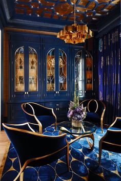 an elegant living room with blue walls and gold trimmings, including two chairs