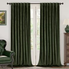 a green chair sitting in front of a window with curtains on the windowsills