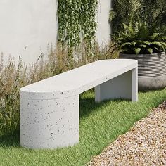 a concrete bench sitting in the grass next to a planter and potted plants