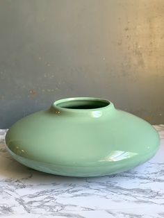 a green vase sitting on top of a white table