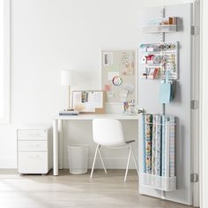 a white desk and chair in a room with lots of papers on the shelf next to it