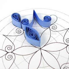 three pieces of blue paper sitting on top of a circular pattern with swirls in the middle