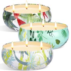 four candles are lit in colorful bowls with tropical designs