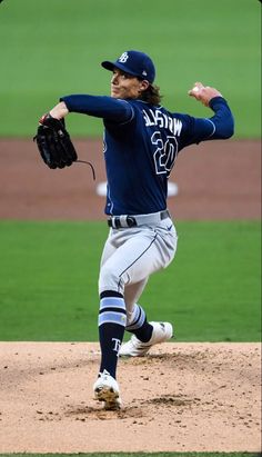 a baseball player pitching a ball on top of a field with his arm in the air