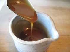 a spoon is pouring caramel syrup into a cup