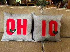 two pillows that have the letters oh and o painted on them sitting on a couch