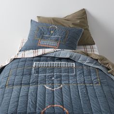 a bed with blue quilted bedspread and matching pillow cases on top of it