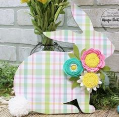 an easter bunny made out of paper with flowers in the vase and eggs on the ground