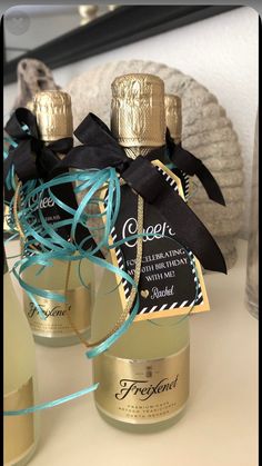 two bottles of perfume sitting on top of a table next to some blue and gold ribbons