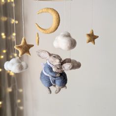 a stuffed animal hanging from a mobile with stars and moon decorations on the wall behind it