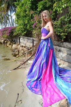 a woman is standing on the beach in a colorful dress and posing for a photo