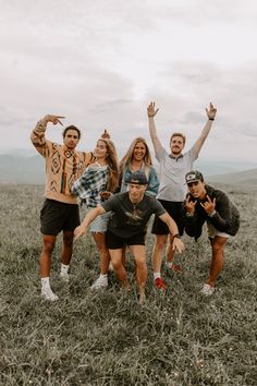 a group of people standing on top of a grass covered field with their arms in the air