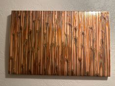 a wooden wall hanging on the side of a white wall with brown and tan stripes