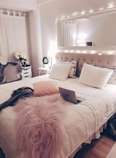 a white bed topped with pillows and a laptop computer sitting on it's side