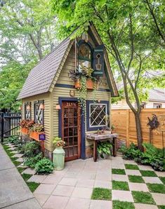 a small garden shed with potted plants on the outside and a picnic table in front