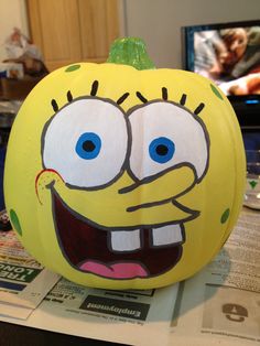 a yellow pumpkin decorated with an image of spongebob's face on it