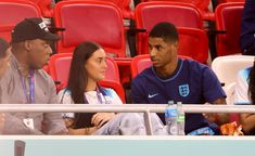 two people sitting next to each other in front of a crowd at a sporting event