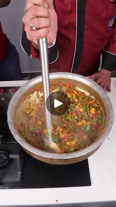 a man cooking food in a pot on top of a stove with a ladle