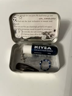 an open tin with some items in it on a white counter top next to a keychain