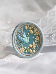 a blue ring with flowers and a bird on the inside is surrounded by white lace