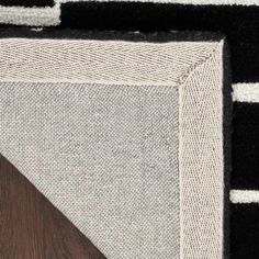 an area rug with black and white stripes on the bottom, dark wood in the middle