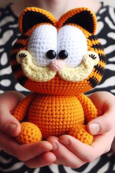 a crocheted stuffed animal in the shape of a tiger is being held by someone's hands